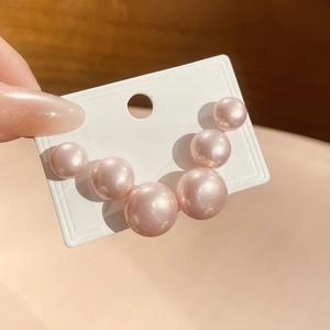 Close-up of elegant pink pearl earrings in a gradient size arrangement on a display card