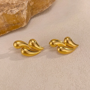 Macro shot of gold teardrop earrings with overlapping layers on a textured rock background