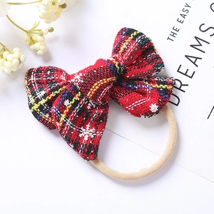 Detail of red plaid Christmas bow headband with snowflake pattern and elastic soft nylon band