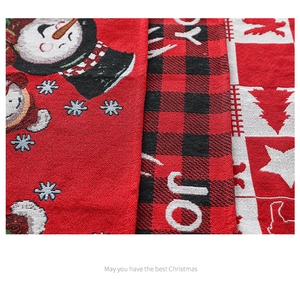 Detailed macro view of woven Christmas table runner fabric with festive elk and JOY patterns