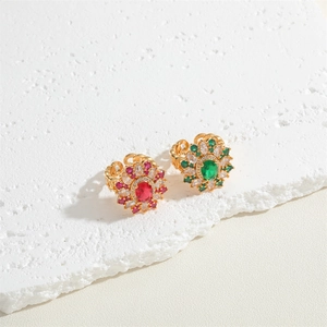 Exaggerated floral gold rings featuring red and green zircon crystals on a textured stone