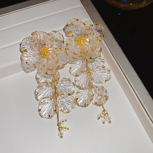 Detail of acrylic flower tassel earrings with frosted petals and gold-edged finish