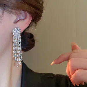 Elegant silver tassel earrings with zircon stones worn by a model in warm soft light