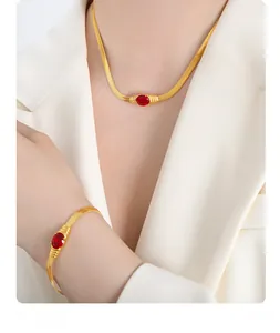 Close-up of golden snake chain jewelry set with red oval gemstone on a female model