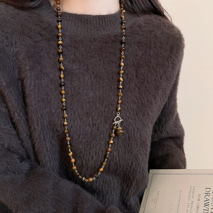 Dettaglio della collana di perline occhio di tigre con grande ciondolo su un maglione