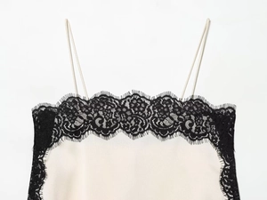 Détail montrant la dentelle noire délicate et le tissu satiné beige sur l'encolure