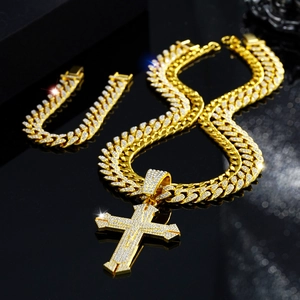 Macro shot of gold cuban chain necklace and bracelet set with iced out cross pendant