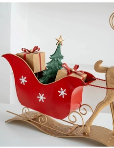 Close-up of red metal Christmas sleigh with gold reindeer and festive gift boxes