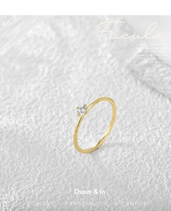 Macro shot of minimalist four-claw setting with round brilliant cut zircon on gold band
