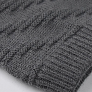 Close-up of thick dark grey cable knit texture and elastic ribbed cuff on winter hat