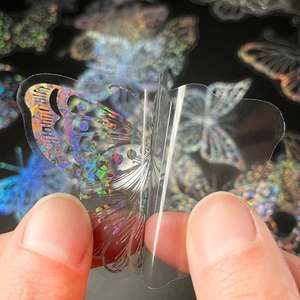 Macro shot showing holographic butterfly PET sticker being peeled with colorful laser effect