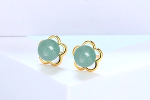 Macro view of gold flower earrings with green aventurine stones on white background