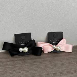 Close-up of pink and black satin bow hair clips with pearls on display cards