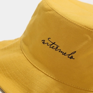 Detail of black watermelon embroidery on a vibrant yellow cotton bucket hat brim