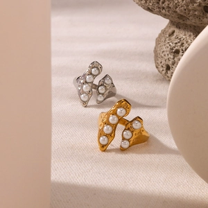 Anelli geometrici in oro 18 carati e argento con perle su sfondo in tessuto beige
