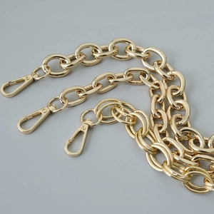 Detailed view of chunky golden metal bag chain strap with secure lobster clasps