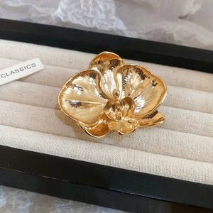 Macro shot of a golden orchid flower brooch with detailed petals on a jewelry stand