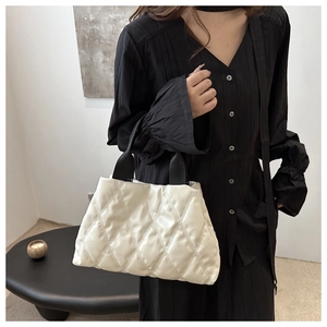 Close-up of quilted white puffer tote bag with black strap and rhombus texture detail