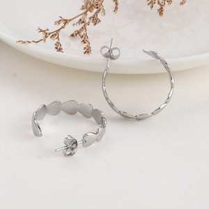 Detailed view of silver heart-shaped C-style hoop earrings on a white display plate