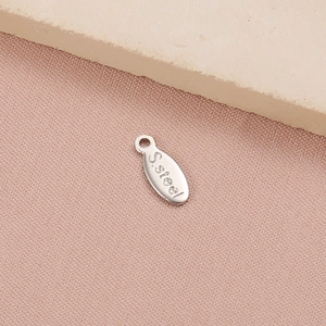 Detailed close-up of a silver stainless steel oval tag charm with S.Steel engraving