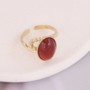 Detail of gold adjustable ring featuring red oval stone and beaded metal texture