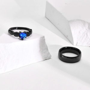 Titanium steel couple rings featuring black bands and a heart-shaped blue zircon stone