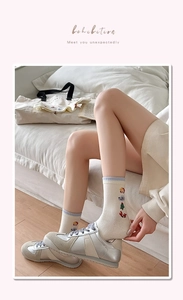 Détail de chaussettes en coton beige avec broderies colorées et bords-côtes bleu ciel