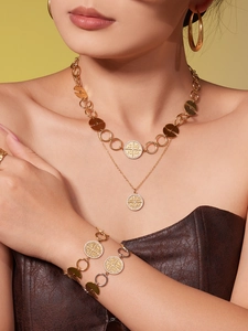 Detailed view of zircon-inlaid gold PVD stainless steel necklace and bracelet set on model