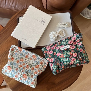 Floral print pleated fabric pouches and lace bow hair clips on a vintage wooden table