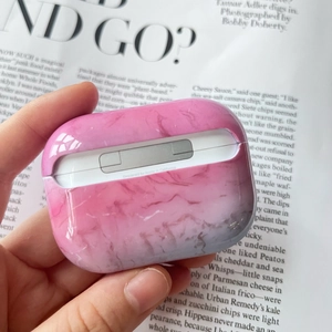 Detail of pink and gray marble PC hard case for AirPods Pro held in hand with magazine