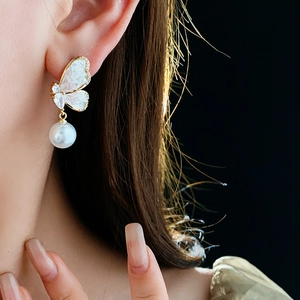 Close-up of elegant butterfly earrings with white pearls and sparkling cubic zirconia stones