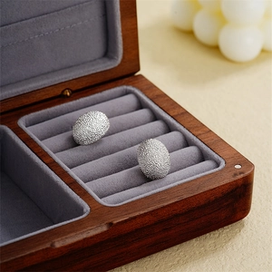 Close-up of silver geometric teardrop stud earrings with textured matte finish in a box