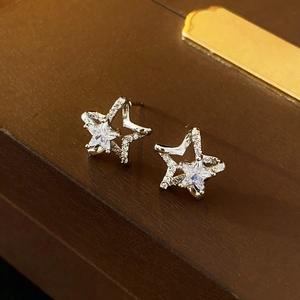 Macro view of glittering silver star earrings with cubic zirconia on a dark wooden background