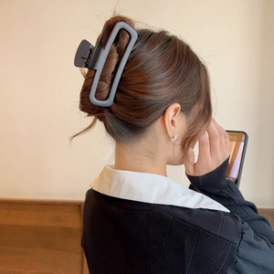 Close-up of a matte dark grey rectangular hair claw clip worn on a woman's hair