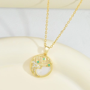 Golden deer pendant necklace with cat-eye opal and green gemstones in minimalist tray