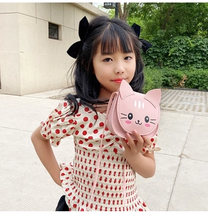 Close-up of a pink cartoon cat crossbody bag made of PU leather worn by a little girl