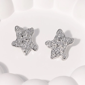Polished silver starfish stud earrings with textured finish on a white ceramic plate