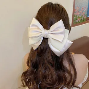 Oversized champagne bow hair clip with layered satin and mesh on brown wavy hair
