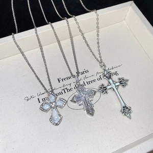 Detailed macro of silver cross necklaces with zircon, mother of pearl and iris flower motif