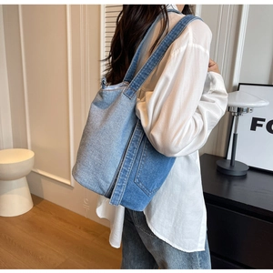 Detail of blue denim bucket bag featuring external pocket and stitched vertical seam detail