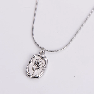 Detail of silver snake chain with oval tulip flower relief pendant on white background