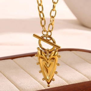Dettaglio della collana con ciondolo a cuore dorato e chiusura a T su vassoio per gioielli