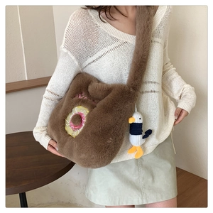 Detail of plush brown shoulder bag featuring donut embroidery and a cute seagull pendant