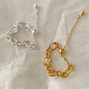 Detail of adjustable chain rings in gold and silver finish on textured paper