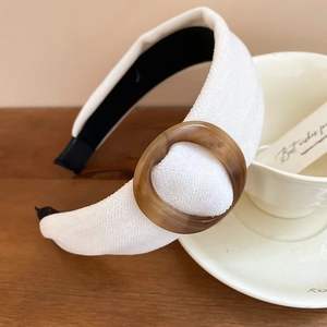 Dettaglio del cerchietto in tessuto crema con decorazione ad anello in resina ambra