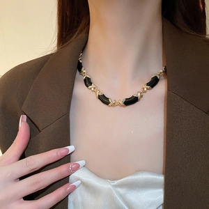 Gros plan d'un collier vintage avec émail noir et maillons dorés en forme de X