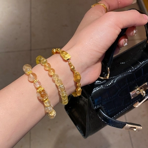 Close-up of yellow citrine beaded bracelet set and zircon flower bangle on female wrist