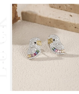 Macro view of parrot stud earrings with colorful zircon and rainbow gemstones on silver