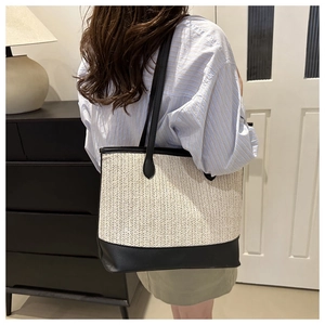Detail view of woven straw tote bag featuring beige herringbone pattern and black trim