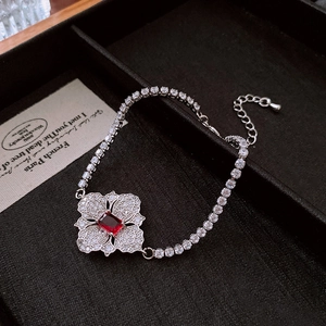 Detail of flower bracelet with a red rectangular gemstone and white zircon stones